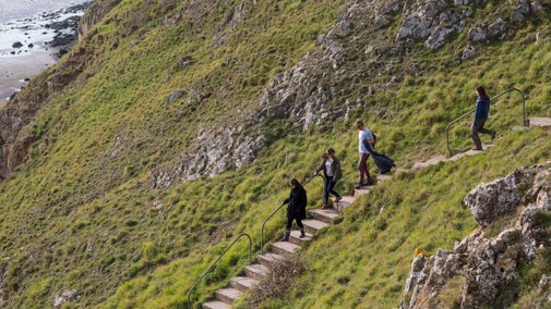 Volunteers climbing down the stairs towards the beach from Brean Down, Somerset, in autumn